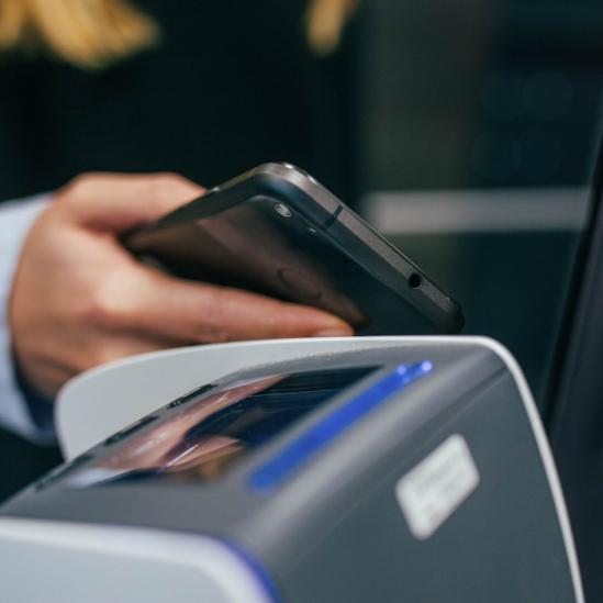 Man in a suit using his smartphone during a bank transaction